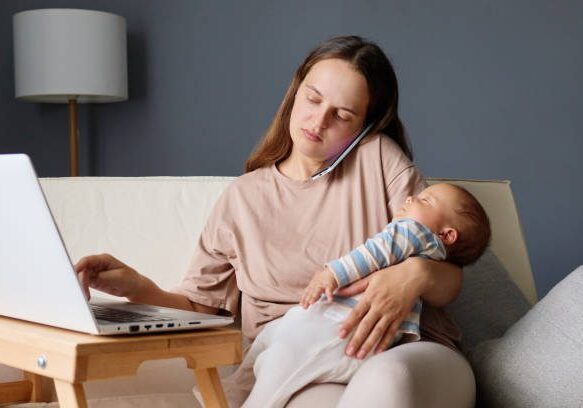 A woman holding her baby while sitting on the couch
