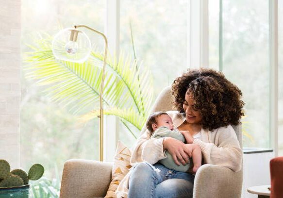 A woman holding her baby in the arms of another person.